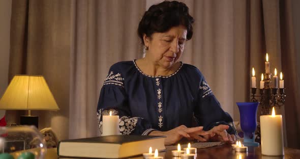 Serious Caucasian Old Woman Talking To Cards Lying at the Table