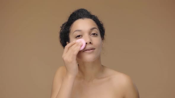 Beauty Portrait of Young African American Woman Cleansing Face with Pink Disc Removing Makeup