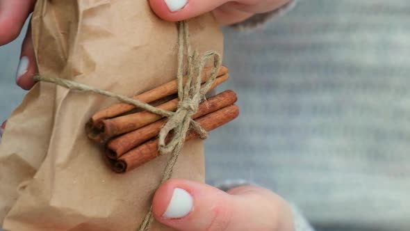 Woman Giving Box with New Year's Gifts Wrapped in Craft Paper and Decorated with Cinnamon Sticks