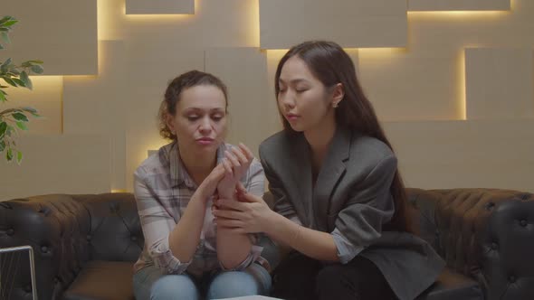 Asian Woman Psychologist Consoling Depressed Female Patient During Psychotherapy