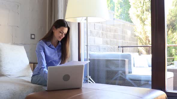 Smiling girl sit on couch watching webinar on laptop. Happy young woman study on online distant cour