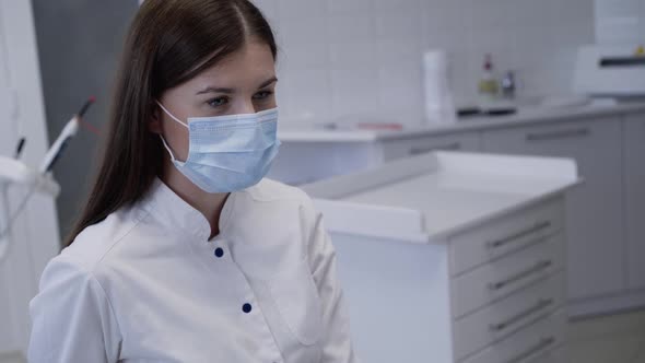 Confident Look of Dentist in Medical Mask Consulting Patient in Clinic