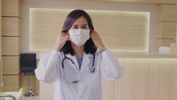 Portrait of Asian female doctor remove protective surgical mask after complete examination job.