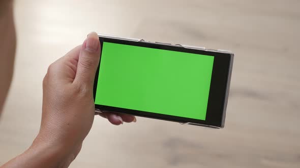 Woman holds modern smart phone with greenscreen display in hands 4K 2160p 30fps UltraHD footage - Fe