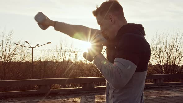 Young and fit man having evening workout outdoor. Urban sunset background.