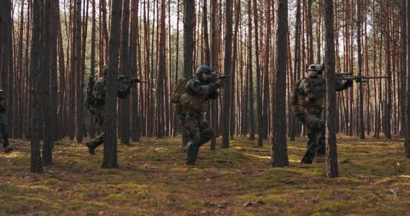 Squad of Four Fully Equipped Soldiers in Camouflage on a Reconnaissance Military Mission Aiming