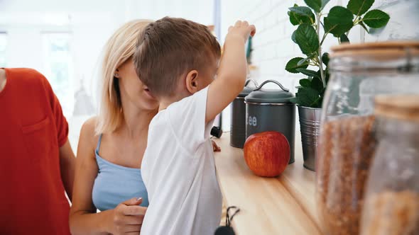 Curious Preschooler Boy Opening Various Containers on the Kitchen Shelf