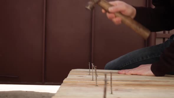 A Man Hammers Nails Into Wooden Boards