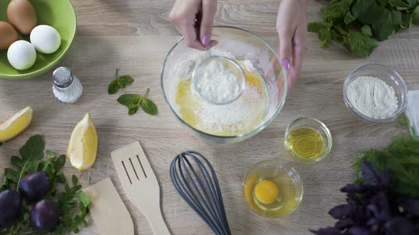 Chef Sieving Flour Over the Glass Bowl with Eggs Before Kneading