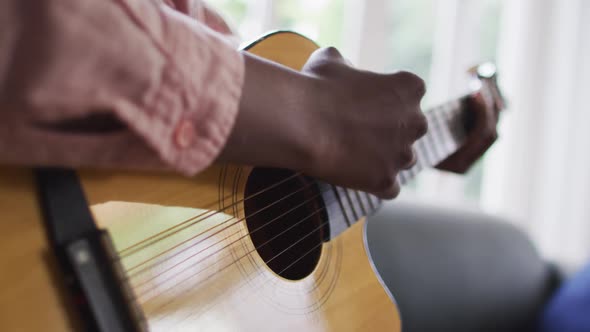 Close up of african american woman playing guitar at home