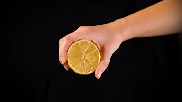 Female Squeezing Lemon Juice on Black Background