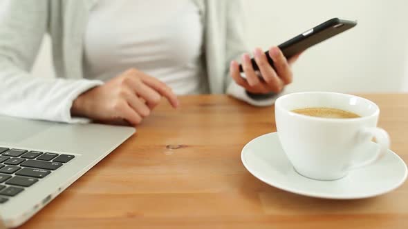 Woman sending text message on mobile phone and drink of coffee