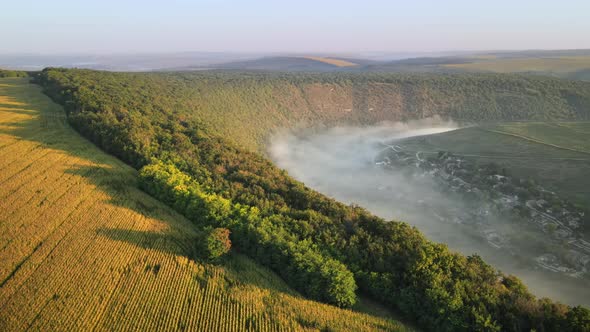 Aerial drone view of the Old Orhei at sunset. Valley with river and fog, village, hills in Moldova