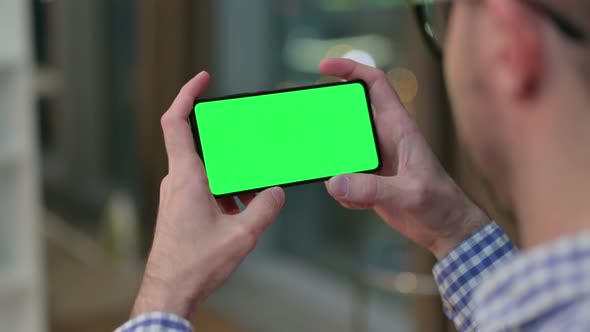 Rear View of Young Man Watching Smartphone with Chroma Key Screen 