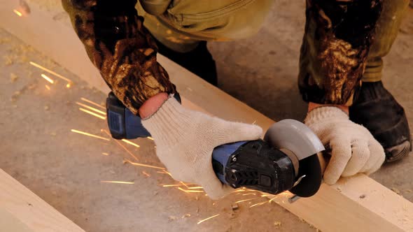 A builder's hands in work gloves cut a metal hairpin with an angle grinder electric tool. Preparatio