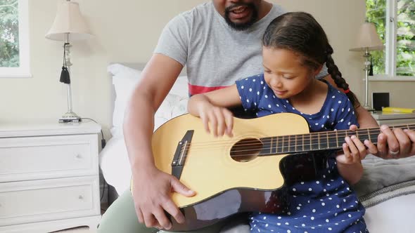 Father and daughter playing guitar in bedroom 4k