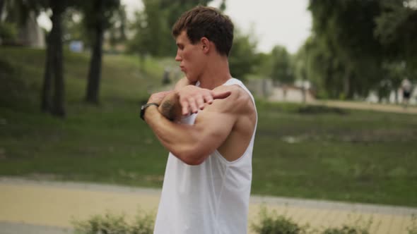 A strong guy is stretching his arms while walking