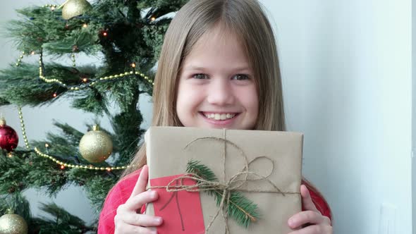 Cute Little Girl Wearing Pajamas Showing Gift Box Advent Calendar with 1 Number at Home Near