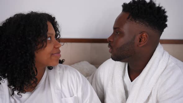 Side View Loving Smiling African American Young Couple Talking Sitting on Bed at Home Indoors