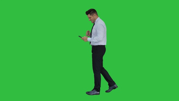 Man walking looking on phone and making win gesture on