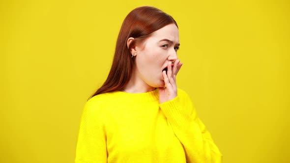 Slim Redhead Woman Yawning at Yellow Background