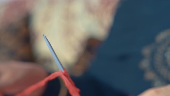 Close up of woman knitting the first row of scarf with red wool. 4k footage of knit work tie-up hand