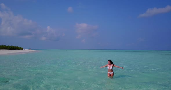 Young fun woman on photoshoot in the sun at the beach on paradise white sand and blue background 4K