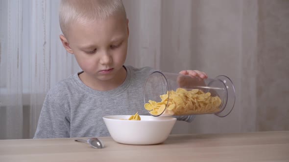 A light-haired little boy is pouring cornflakes into a plate.