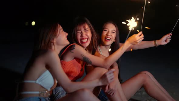 4K Group of Asian woman playing sparklers together on tropical island beach in summer night.