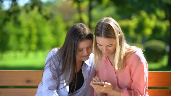 Two Funny Female Friends Scrolling and Discussing Photos of Men in Dating App