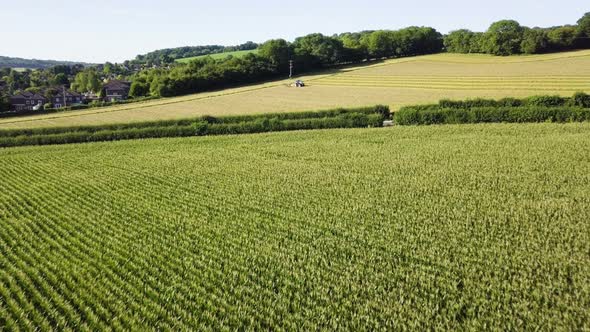 Aerial footage of corn field and farm land with a tractor harvesting a field