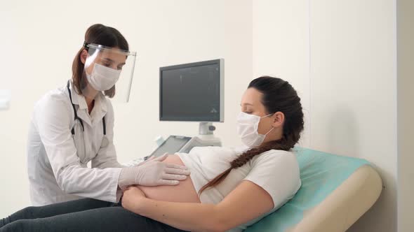 Doctor in Mask and Gloves Examining Tummy of Pregnant Woman