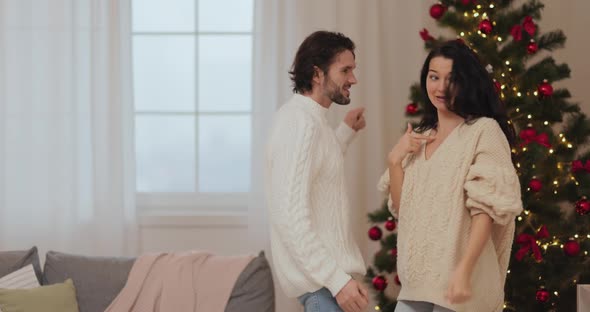Funny Dancing Couple Celebrating New Year Near Christmas Tree at Home