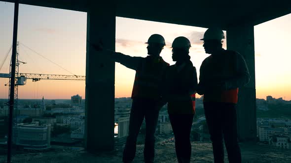 Working Engineers Discuss Job While Standing on a Construction Site alt