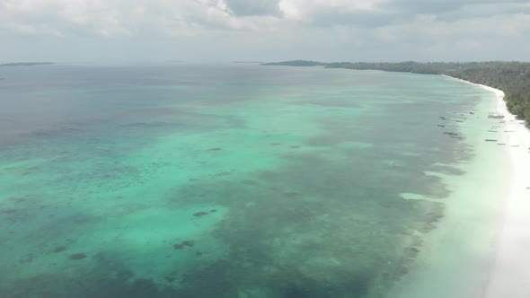 Aerial: flying over tropical beach coral reef turquoise water green forest uncon