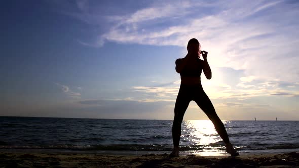 Female Fighter Is Training Strikes By Legs in Sea Shore in Summer Day, Silhouette of Her Body