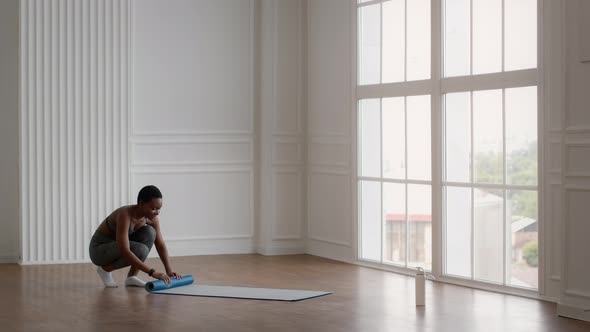 Young Sporty African American Woman Rolling Down Fitness Mat After Training at Home