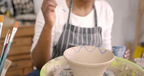 Young Black Woman Painting a Clay Bowl at Workshop