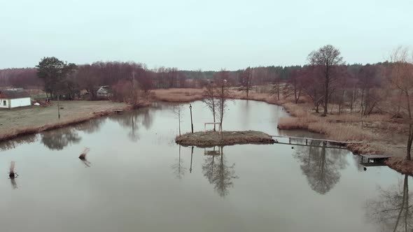 Small lake with village houses surrounded by tree forest, drone shot view