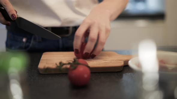 Handheld Shot of Woman Chopping Cherries on a Wooden Board