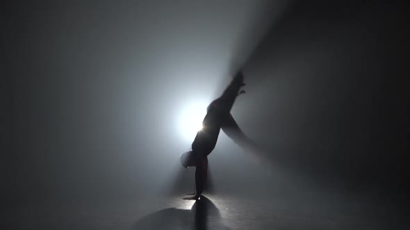 Man Practicing Capoeira in Darkness Against Spotlight in Dark Studio