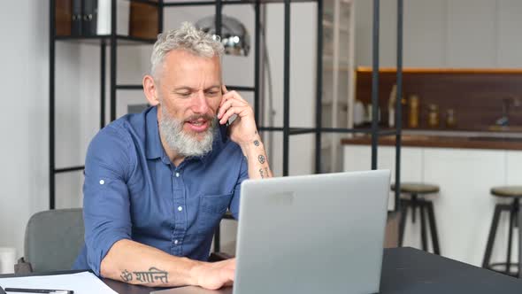 Mature Greyhaired Male Entrepreneur Using Laptop in the Home Office