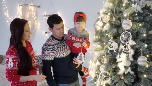 Parents with Daughter Decorate Illuminated Christmas Tree