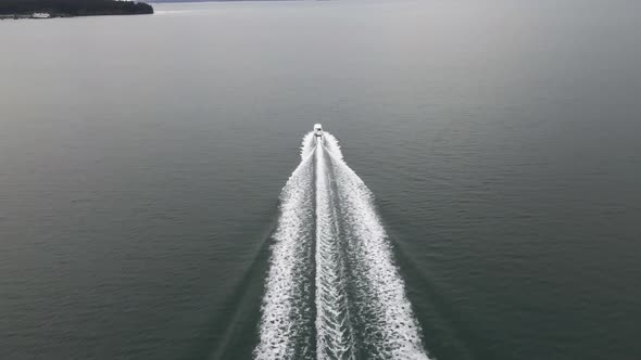A lone boat speeds through the dark gray green waters of Puget Sound and the Salish Sea, aerial