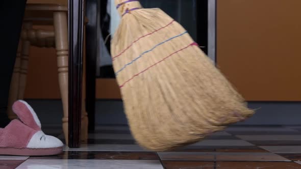 Young Girl Sweeps the Floor in the Kitchen with an Ordinary Broom in Slow Mo