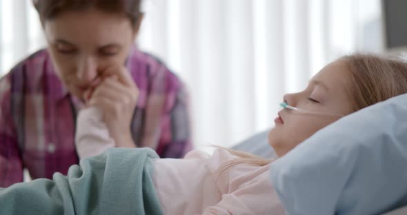 Close Up of Mother Holding Hand of Recovering Little Child Lying in the Hospital Bed Sleeping