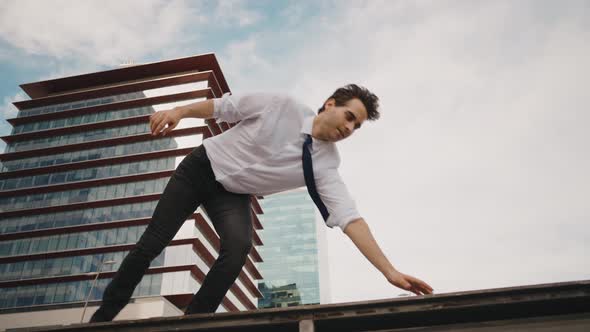 Flexible and cool businessman doing acrobatic tricks outdoor.