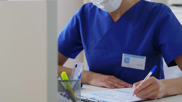 Doctor or Nurse in Mask with Clipboard at Hospital