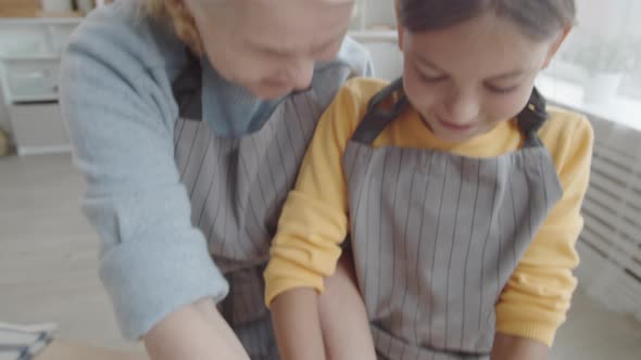 Grandmother and Granddaughter Making Dough Together at Kitchen Table