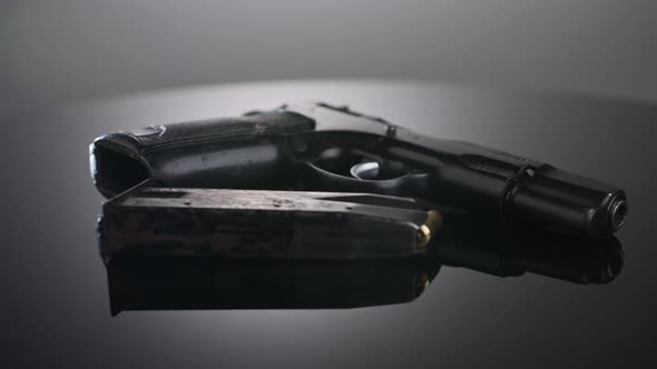 Gun Control. Studio shot of a 9mm gun rotating on a reflective surface